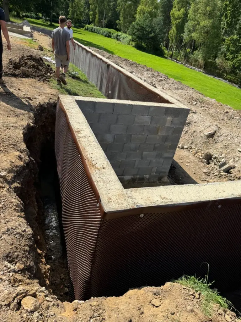 Excavated ground around below-ground blockwork with a protective membrane.