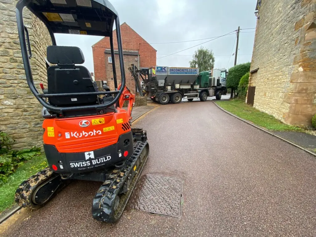 Swiss Build’s compact digger on site with a concrete delivery lorry behind it.